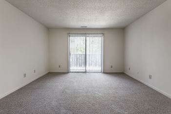 an empty living room with a sliding glass door to a balcony at The Timbers Apartments, Evansville, IN